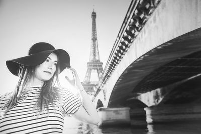 Woman sitting on bridge with city in background