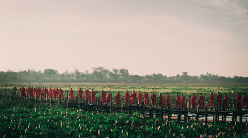 Monks standing on field against sky during sunset