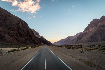 Road leading towards mountains against sky