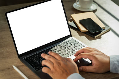 Cropped hands using laptop on table