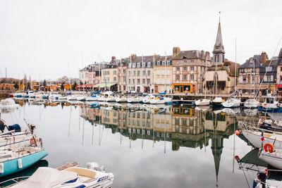 Boats moored at harbor against buildings in city