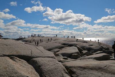 People on rock formation against sky