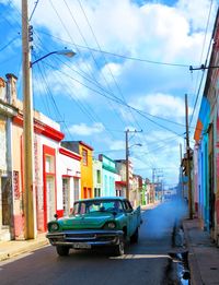 Cars on street in city against sky