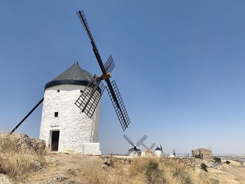 Traditional windmill on field against clear blue sky