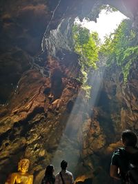 Rear view of people standing in cave