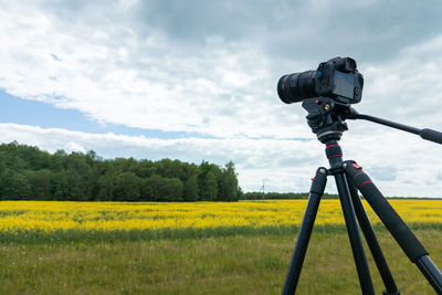 Modern professional mirrorless camera on tripod shooting yellow field on tripod, closeup