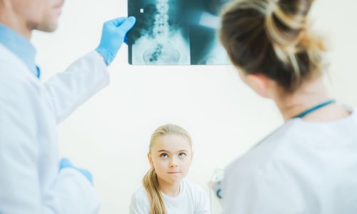 Girl looking at doctors with x-ray at hospital