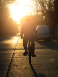 Rear view of man riding bicycle on street