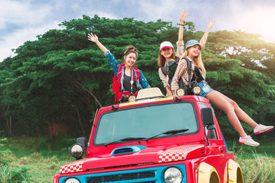 Happy friends sitting on vehicle