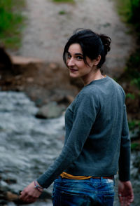 Rear view portrait of woman looking over shoulder while standing outdoors