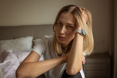 Portrait of young woman sitting on bed at home