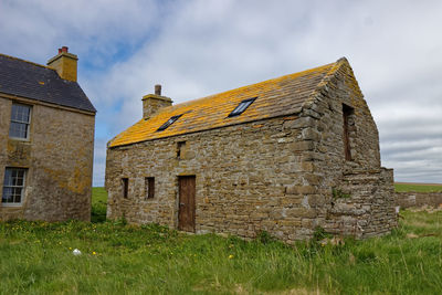 Exterior of old house on field against sky