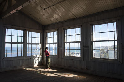 One woman watching through some windows at an old building./