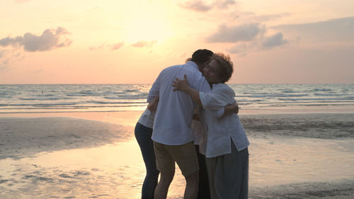 Couple standing on beach during sunset