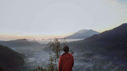 Rear view of man looking at mountains against sky