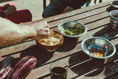 Cropped hand of man holding food on wooden table