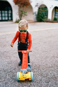 Rear view of boy skateboarding on road