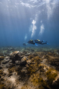 Young friends scuba diving over ocean floor undersea