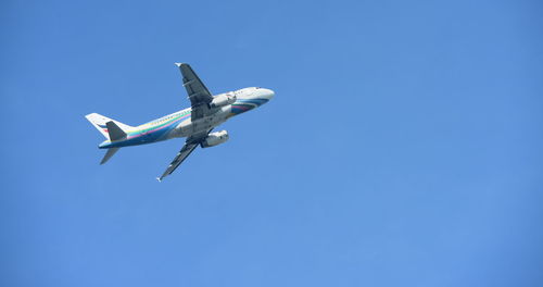 Low angle view of airplane flying against clear blue sky