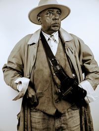 Midsection of man holding hat against white background