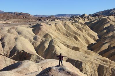 Rear view of man standing on rocky mountain