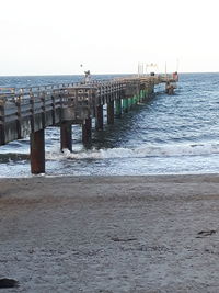 Wooden posts on beach against clear sky