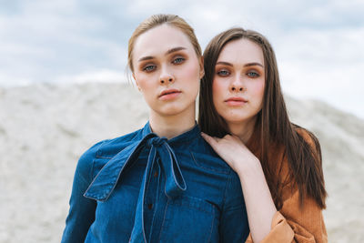 Fashion beauty portrait of young women sisters in brown velvet jeans shirts on desert background