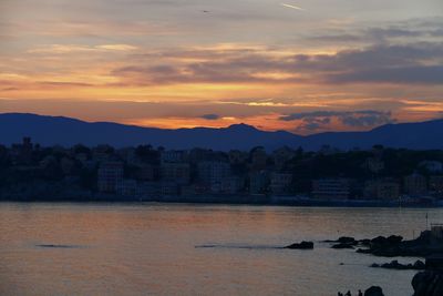 Scenic view of sea and cityscape against sky during sunset