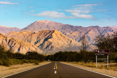 Road leading towards mountains against sky