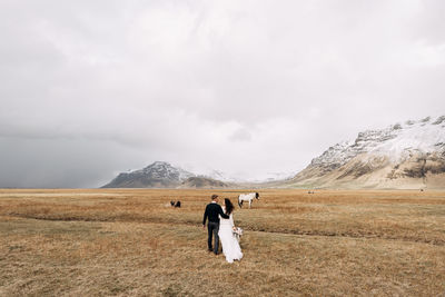 Rear view of couple walking on field