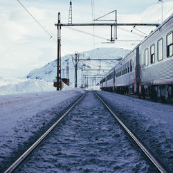 Train by railroad track against sky during winter