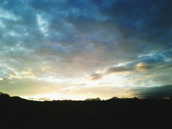 Low angle view of silhouette trees against dramatic sky