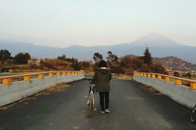 Rear view of people standing on road against mountain