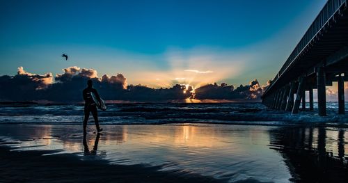 Silhouette person standing on beach against sky during sunset