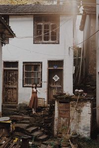 Woman standing by window of old building