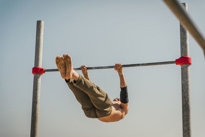 Male athlete exercising on high bar