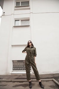 Female fashion model, posing for a full length photo, wearing green suit, urban fashion photography