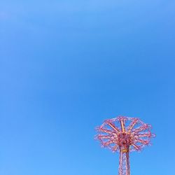 Low angle view of amusement park ride against clear blue sky at coney island