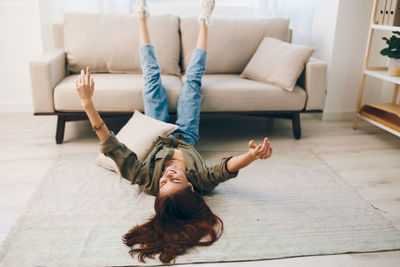 Full length of woman sitting on sofa at home