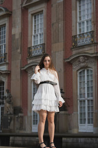 Portrait of a young woman standing against building