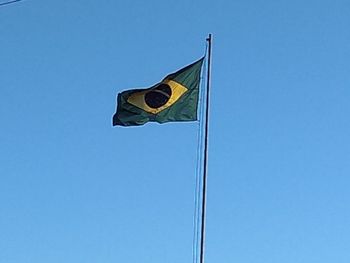 Low angle view of flag against clear blue sky