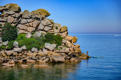 Rock formation by sea against clear sky