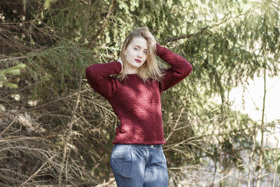 Portrait of young woman standing by tree