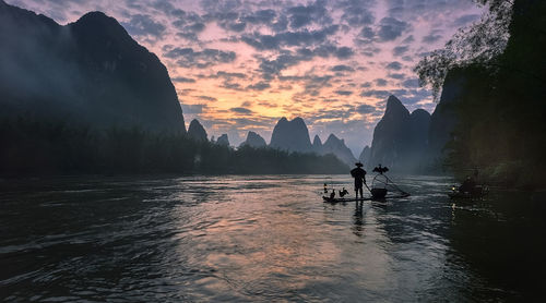 Man on boat against sky during sunset