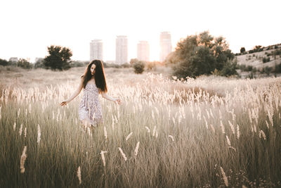 Young woman walking amidst plants on field