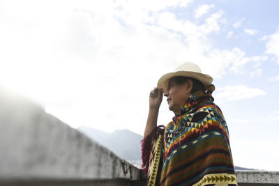 Indigenous man wearing hat while standing at rooftop