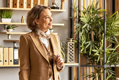 Portrait of a business smiling woman in a suit in the office at work. woman's hands hold glasses 