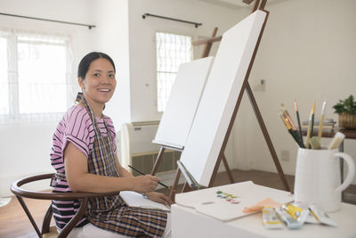 Portrait of smiling woman painting on canvas at home