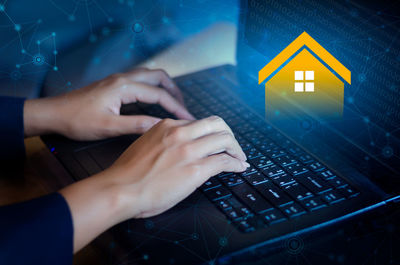 Digital composite image of woman using laptop with house icon