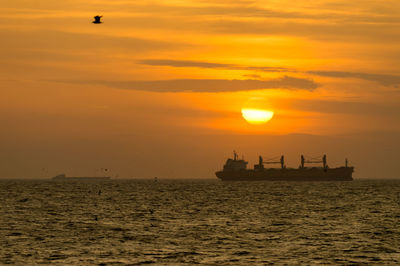 Silhouette boat in sea against sky during sunset